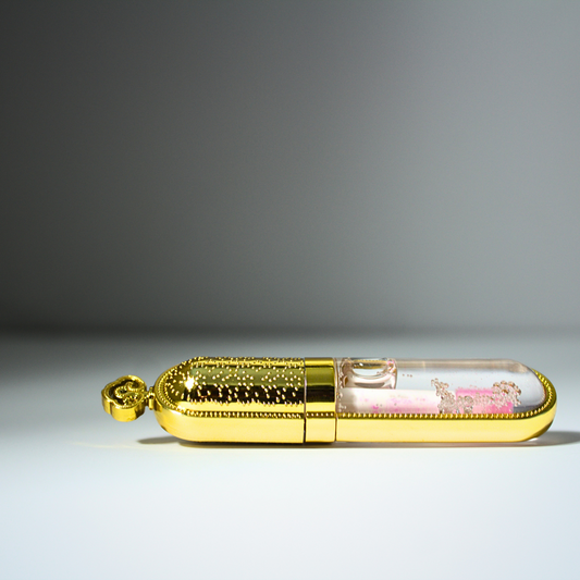 Clear color changing lip gloss in gold and clear tube laying down Liv 4 You 2